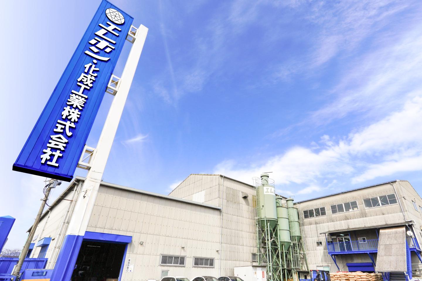 エフシン化成工業株式会社の外観。青い看板と工場の建物が見える。